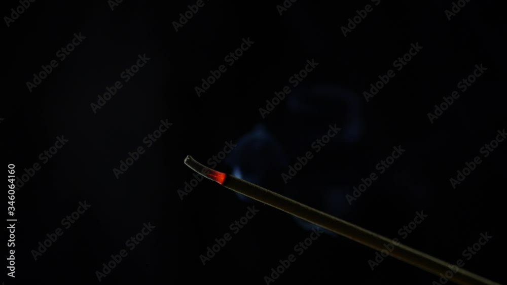 Close-up view of burning incense stick. Smoke blows from end of hot ember. Scent released from incense on black background. Relaxation, meditation and aromatherapy. 4k Close-up view of burning incense stick. Smoke blows from end of hot ember. Scent released from incense on black background. Relaxation, meditation and aromatherapy. 4k