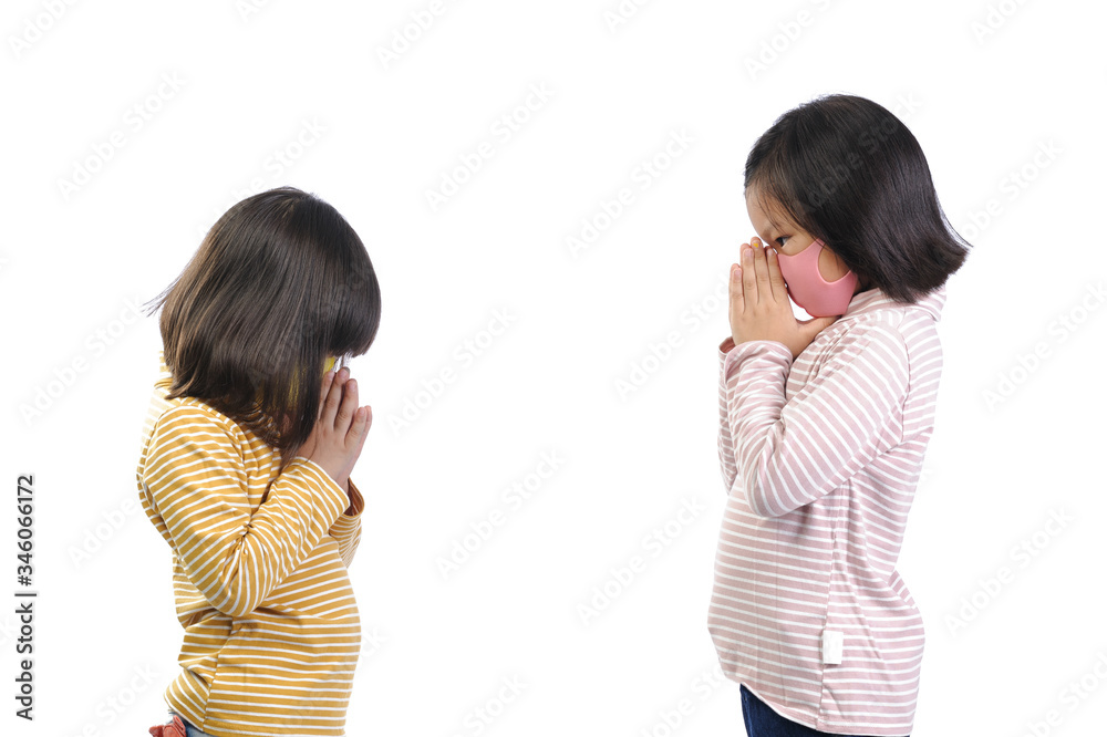 Social distance concept. Two little adorable Asian kids wearing a self-protect mask standing distance at 1meter and Greet with respect instead of hands touch (say hi to namaste) for safety. Social distance concept. Two little adorable Asian kids wearing a self-protect mask standing distance at 1meter and Greet with respect instead of hands touch (say hi to namaste) for safety.