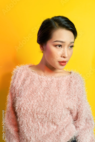 Inspired asian young woman dancing in studio and laughing. Pretty girl in cute dress jumping on yellow background.