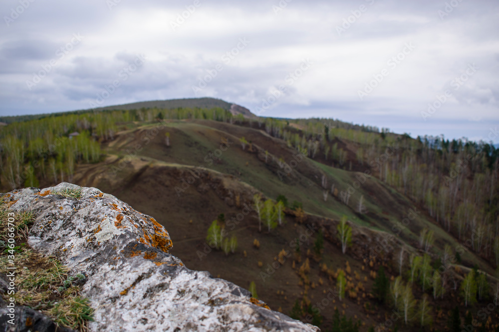 Rock is light gray. Brown lichen. Mountains and green forest in blur. Rock is light gray. Brown lichen. Mountains and green forest in blur.