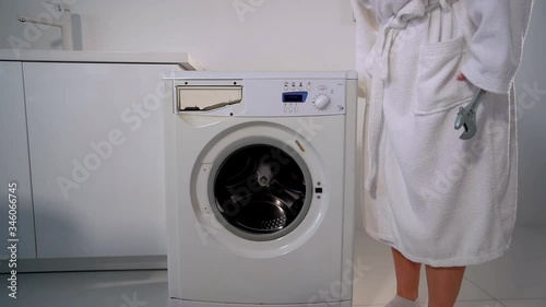 A young woman beats and breaks washing machine