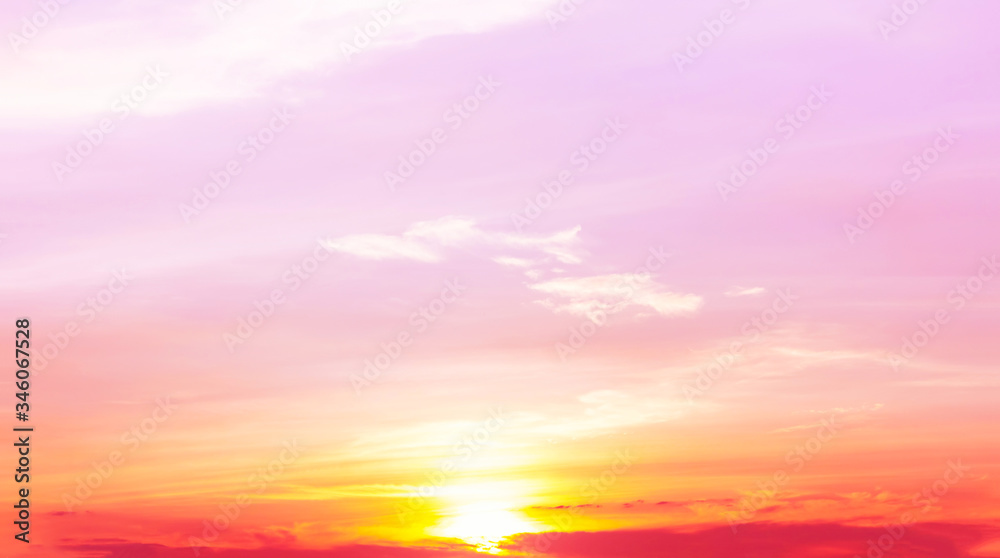 sunset with orange and yellow light in pink sky and soft clouds