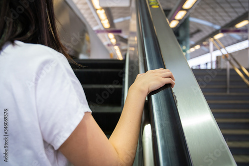 Woman grabbing the escalator hand rail while standing on the escalator