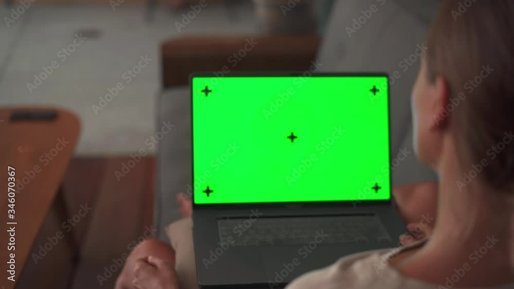 Woman watching on laptop green screen sitting reaxed on sofa Woman watching on laptop green screen sitting reaxed on sofa