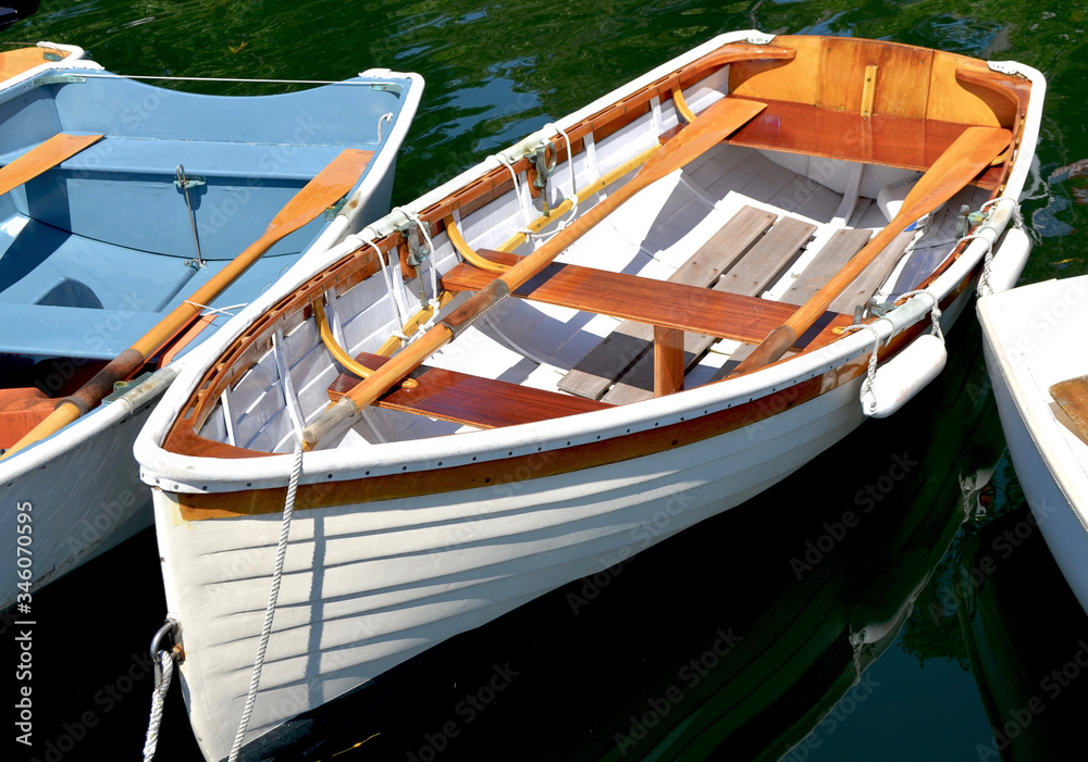 A classic downeast lapstrake rowboat is tied up with other small boats at a dock in coastal Maine.  Closeup.