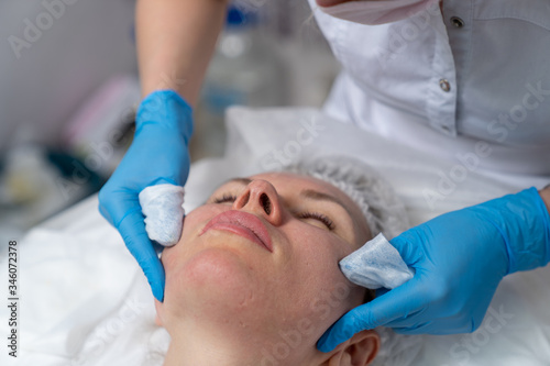 Beautician does facial skin cleansing for his client. Cleansing the skin with special tools. Facial cleansing mask.