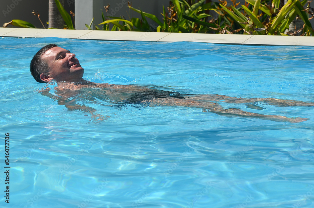Young beauty caucasian man swimming and relaxing in the swimming pool in summer vacation lifestyle