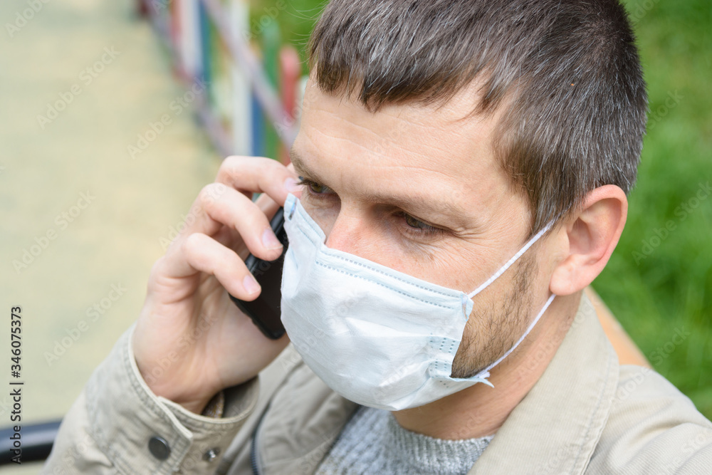 Close-up of a man in a medical mask talking on the phone