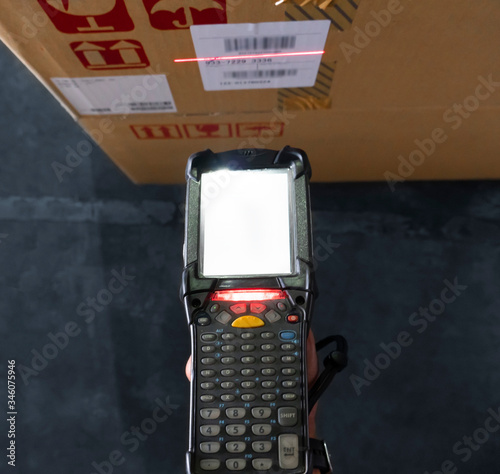 close up hand holding bar code scanner with scanning red laser on label of product, warehouse inventory management.