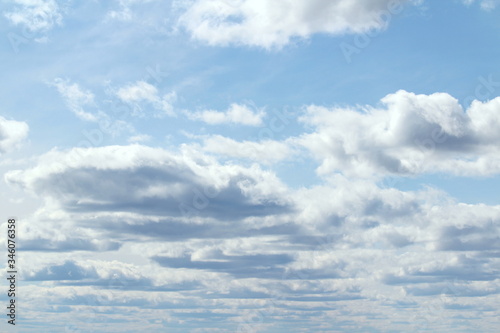 Clouds in the blue sky at sunset or dawn backlit by the sun. Place for text and design.