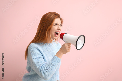 Emotional woman with megaphone on color background