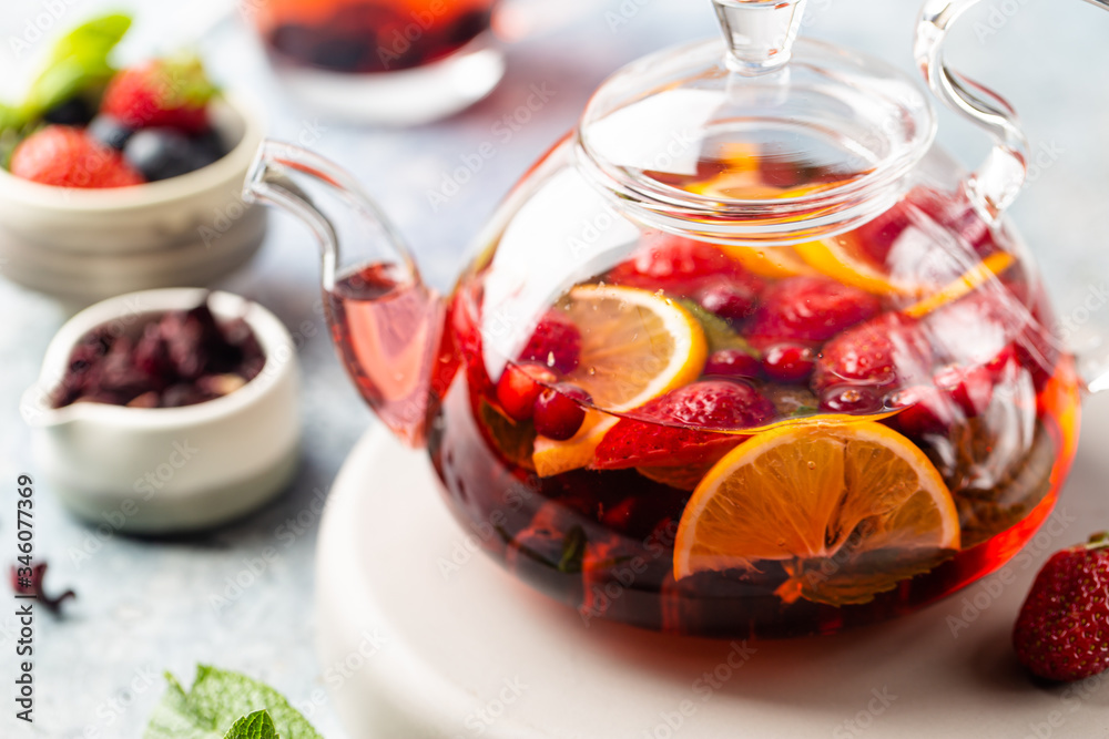 Fruit red tea with berries in glass teapot on white background Fruit red tea with berries in glass teapot on white background