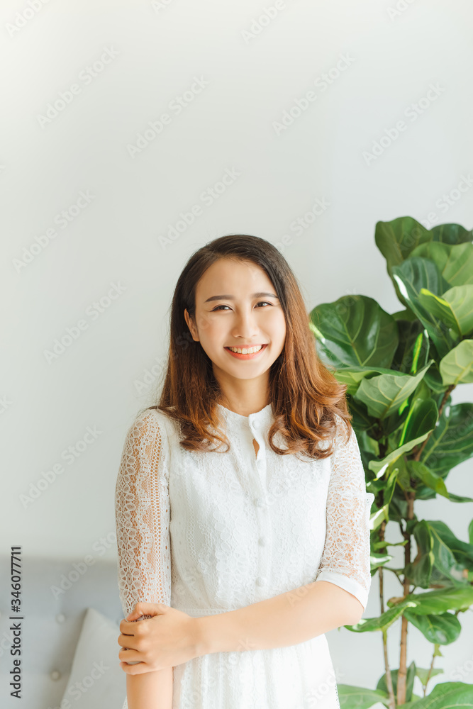 Cheerful young Asian woman standing in her room Cheerful young Asian woman standing in her room