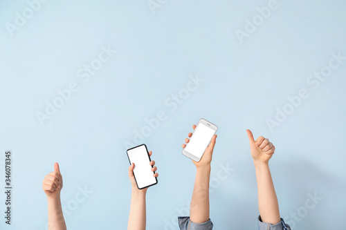 Female hands with mobile phones on light background