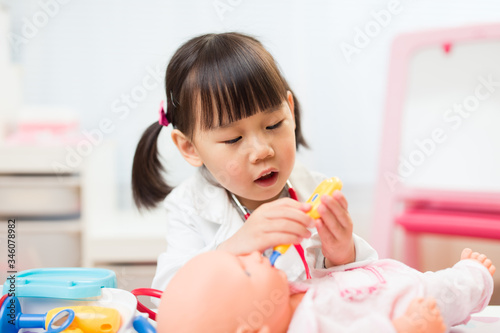 toddler girl pretend play doctor role at home against white background