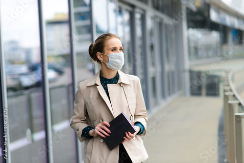 A young businesswoman wearing a health mask and talking on the phone in the city