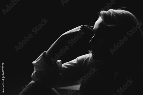Silhouette of a beautiful young blonde woman in low key. Black and white art photo. Soft selective focus.
