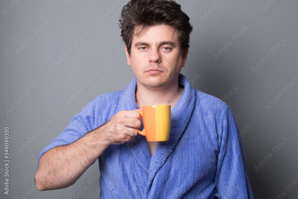 Sleepy man in a bathrobe drinks morning coffee or tea. Sleepy man in a bathrobe drinks morning coffee or tea.