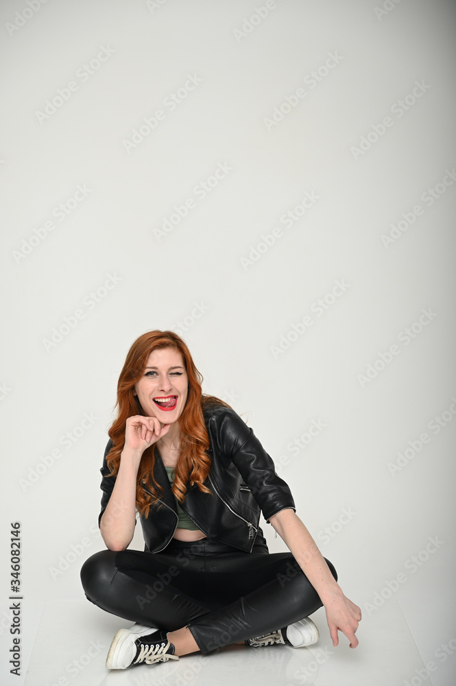 Young woman shows emotions changing poses while sitting on the floor. Portrait of a pretty girl with beautiful hair in a green T-shirt and black clothes on a white background. Young woman shows emotions changing poses while sitting on the floor. Portrait of a pretty girl with beautiful hair in a green T-shirt and black clothes on a white background.