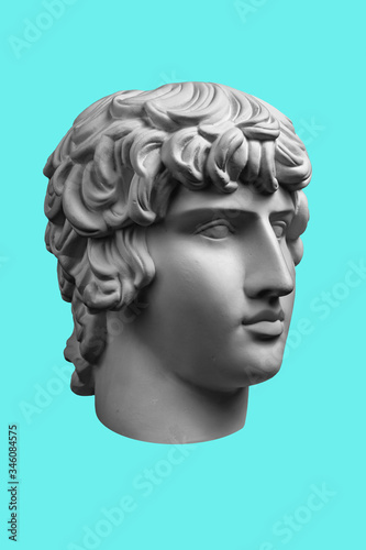 Gypsum copy of ancient famous statue Antinous head isolated on a light green background. Plaster antique sculpture young man face. Renaissance epoch.