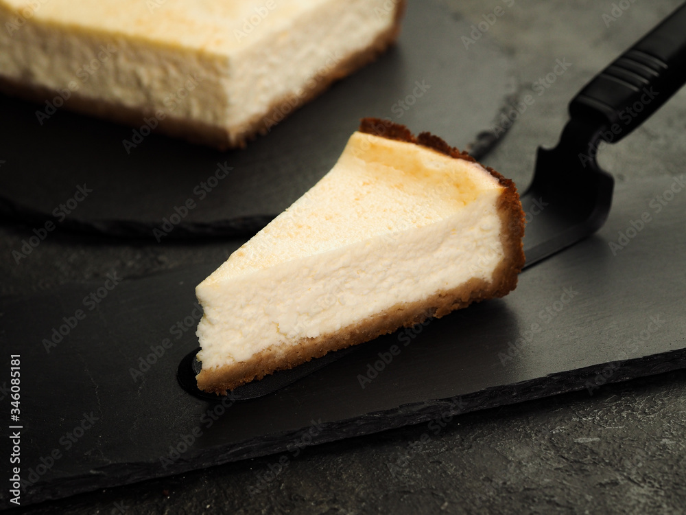 composition with a delicious homemade classic New York cheesecake and a slice on a dark background