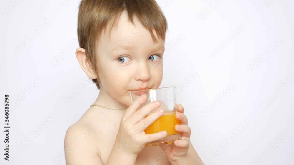 A beautiful naked boy drinks fresh orange juice from a glass A beautiful naked boy drinks fresh orange juice from a glass
