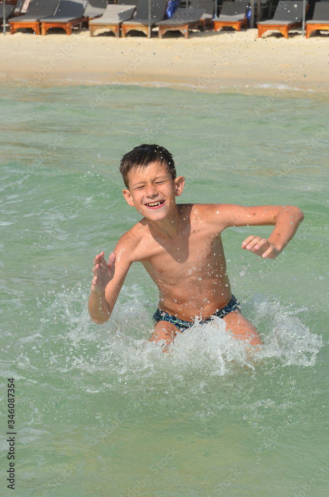 A happy caucasian child is swimming in the sea on summer vacation. A boy in a splash of water on a sunny day lifestyle