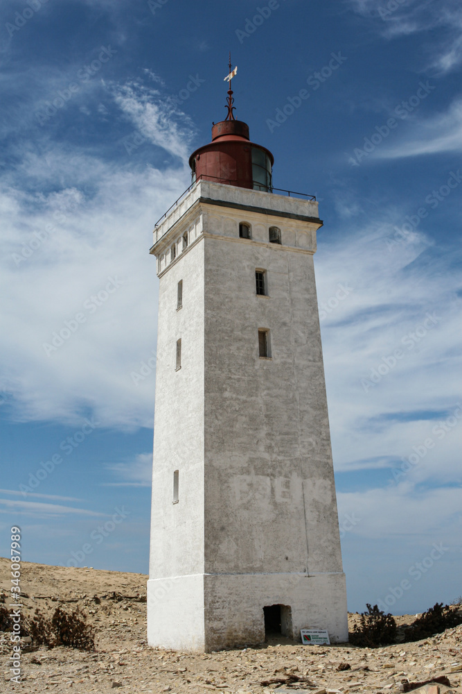 LIghthouse with blue sky and clouds råbjerg knude in skagen denmark LIghthouse with blue sky and clouds råbjerg knude in skagen denmark