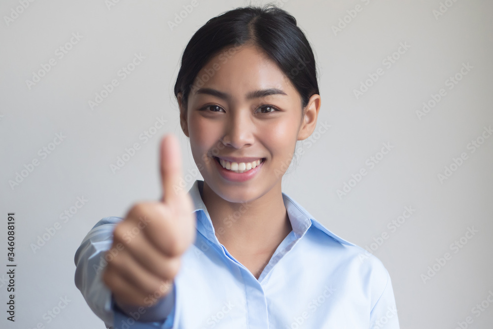 successful girl pointing thumb up; portrait of cheerful smiling office worker woman pointing up approving, yes, ok, good, thumb up gesture; southeast asian woman young adult model successful girl pointing thumb up; portrait of cheerful smiling office worker woman pointing up approving, yes, ok, good, thumb up gesture; southeast asian woman young adult model