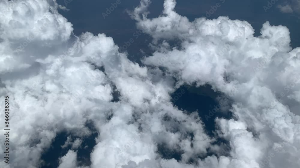 Scenic aerial view through moving white clouds. Flying through beautiful thick fluffy clouds. view from the airplane window. low light Scenic aerial view through moving white clouds. Flying through beautiful thick fluffy clouds. view from the airplane window. low light