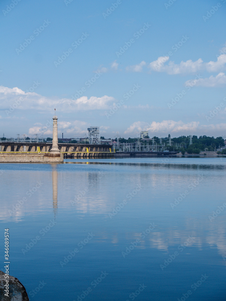 Fototapeta premium river pier. blue water. summer day at the river pier. clouds in the sky are reflected in the river.