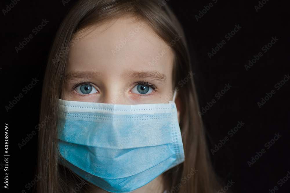 Close-up portrait of little defenseless girl on black backgound in blue disposable mask for protection of Coronavirus Covid-19 during self-isolation at home Close-up portrait of little defenseless girl on black backgound in blue disposable mask for protection of Coronavirus Covid-19 during self-isolation at home