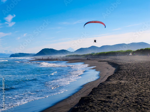 Paraglider over the Halaktyr black sand beach in the sunset