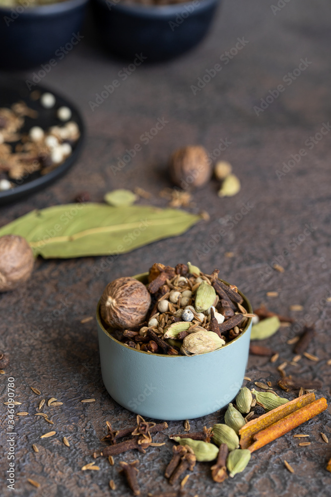 Fototapeta premium Different spices black and white peppercorns, cloves, cinnamon, mace, cardamom, cumin. Spice blend of ground spices in metal bowl on lthe table