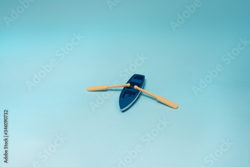 Small boat with oars on blue background