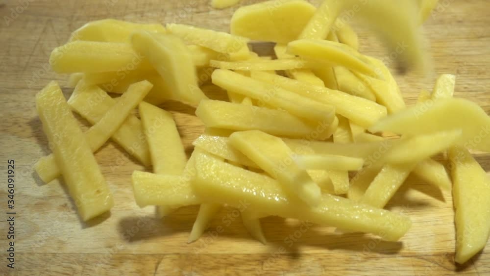 Slices of raw chopped potatoes fall in slow motion on a wooden cutting board. Close-up Slices of raw chopped potatoes fall in slow motion on a wooden cutting board. Close-up