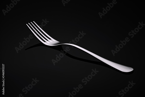 A white metal fork rests on a black glass.