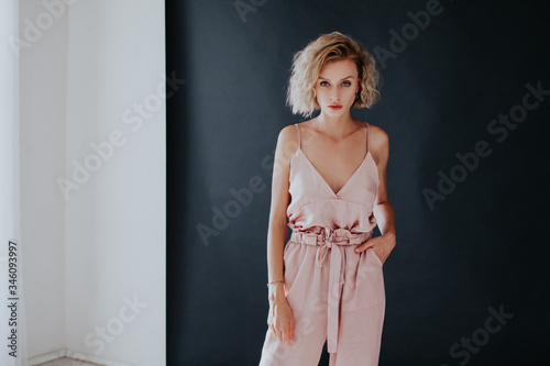 Beautiful fashionable blonde woman in pink dress on a white black background photo