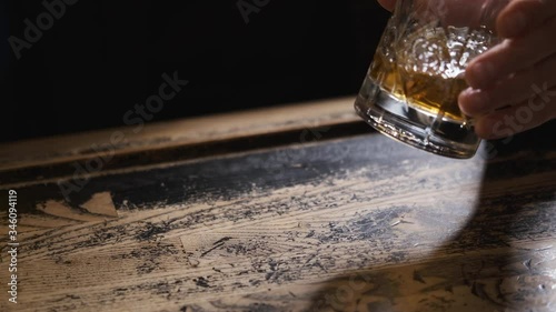 hands with glass on bar,glass rolling on table,man at bar,bokeh,bartender puts ice and takes glass of Bourbon, whiskey.order at bar,splashes of alcohol,concept alcohol, bar.Close-up, 4k