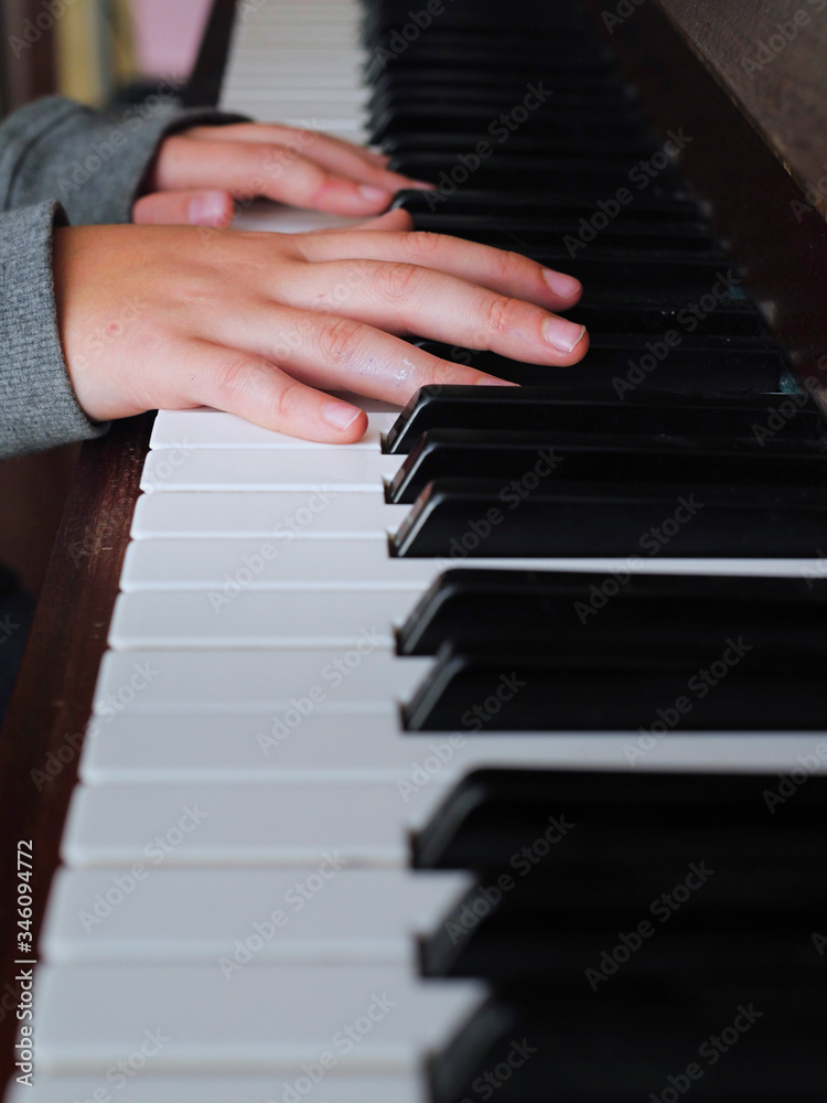 Teenager hand on piano keys, grey sleeves , Concept music practice
