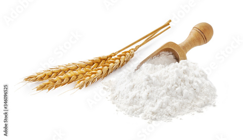 Wheat flour with spikelets and wooden scoop isolated on white.