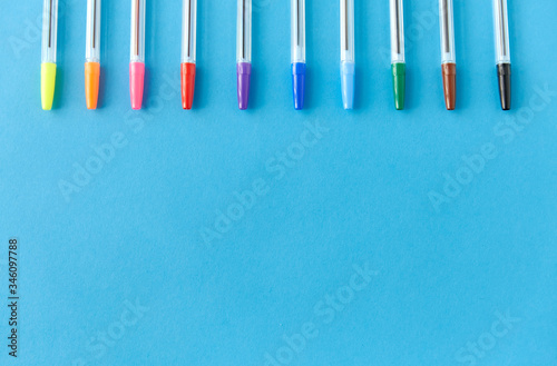 school  writing tools and object concept - row of many multicolored pens on blue background