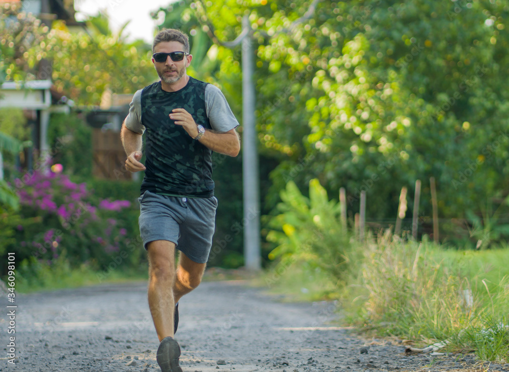 outdoors jogging workout - young attractive and happy man in sport clothes and sunglasses running in city park enjoying fitness in sport and healthy lifestyle concept outdoors jogging workout - young attractive and happy man in sport clothes and sunglasses running in city park enjoying fitness in sport and healthy lifestyle concept