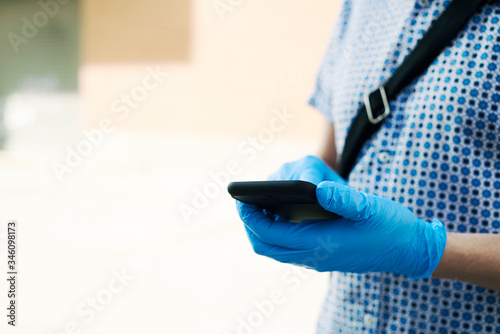 man wearing latex gloves using his smartphone