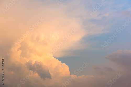 Fluffy clouds glowing pink at sunset against a blue sky.