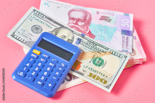 Heap of different money and calculator on pink background. Payment concept
