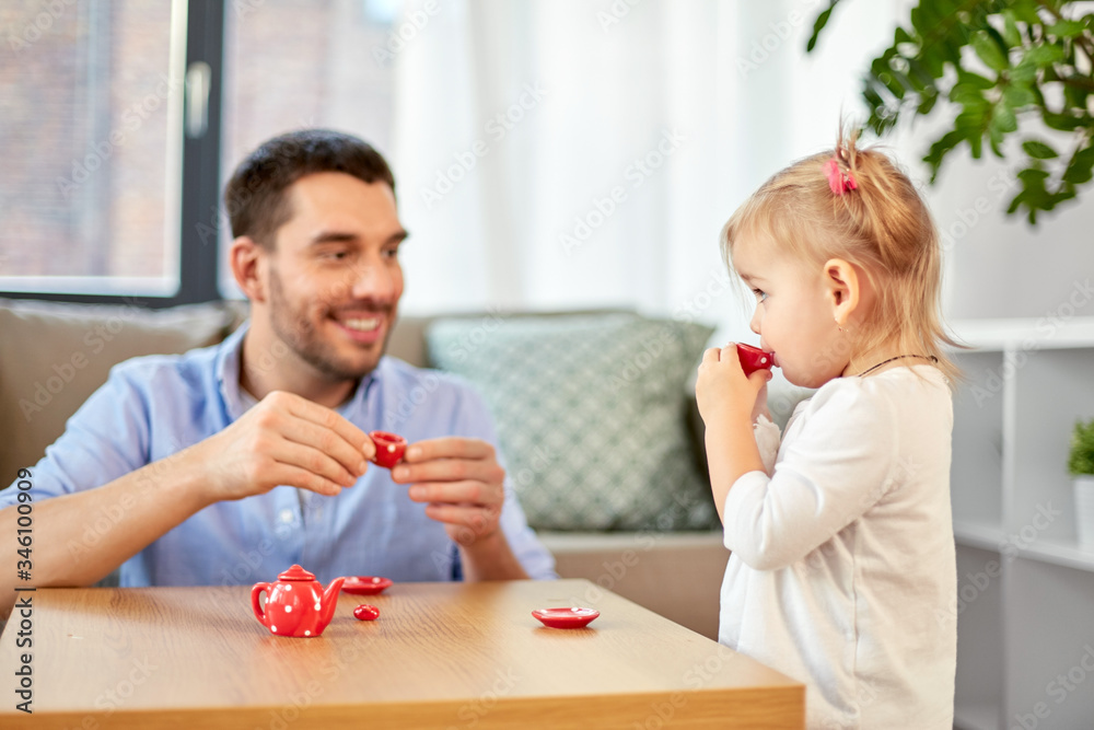 family, fatherhood and childhood concept - happy father and little daughter with toy crockery playing tea party at home family, fatherhood and childhood concept - happy father and little daughter with toy crockery playing tea party at home