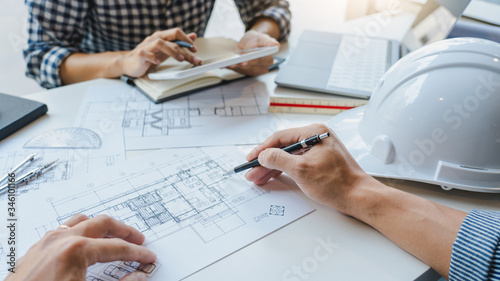 Obraz na plátně engineer Hand Drawing Plan On Blue Print with architect equipment discussing the floor plans over blueprint architectural plans at table in a modern office