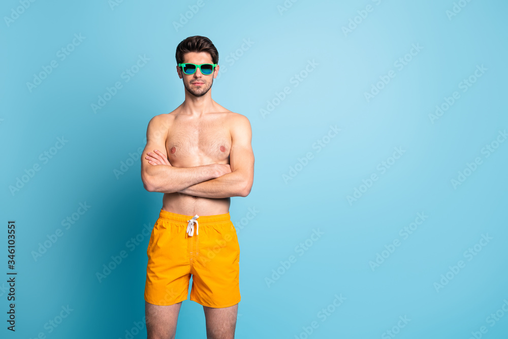 Portrait of his he nice attractive content virile masculine muscular guy wearing swimming shorts folded arms isolated over bright vivid shine vibrant green blue turquoise color background