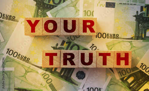 Your truth word written on wooden cubes laying on 100 Euro bills. Earning first money storytelling concept photo